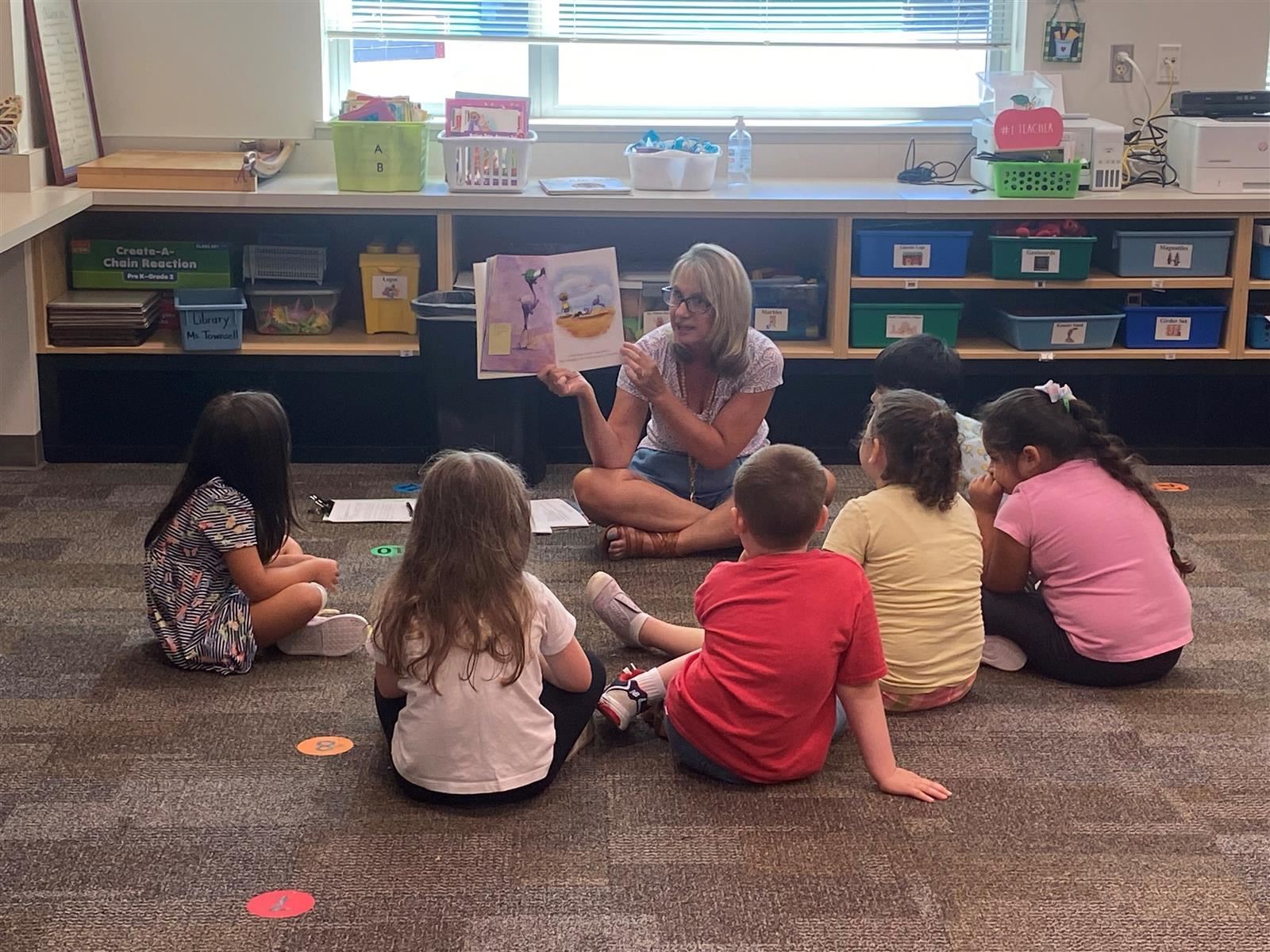 teacher reading to kids sitting in a circle teacher reading to kids sitting in a circle